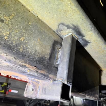 Welded metal beam showing rust and imperfections on a vehicle frame.