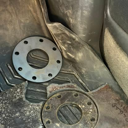 Two metallic flanges on a textured surface inside a vehicle, showcasing vehicle repair components.